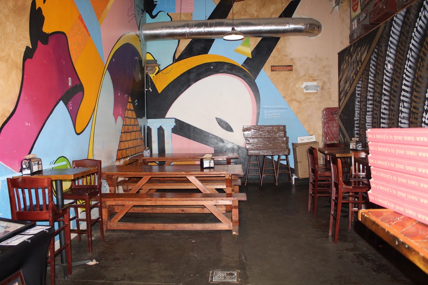Wide view of Benny Pennello's dining room with colorful mural and wooden picnic tables