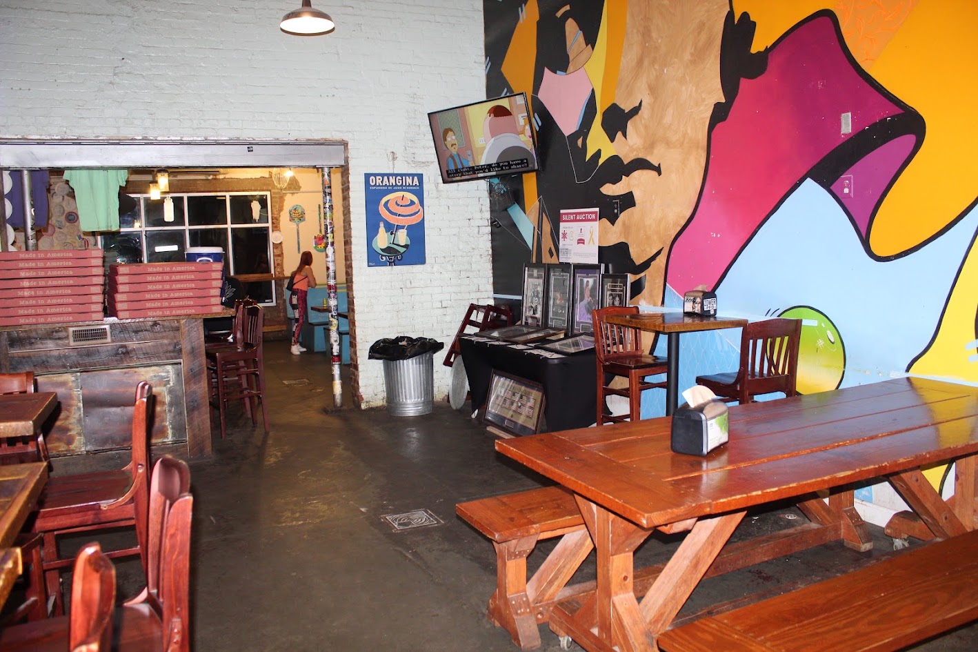 Dining tables and mural inside Benny Pennello's Pizza in Charlotte