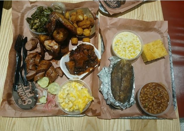 Overview of barbecue plates with smoked meats and sides at The Smoke Pit Charlotte
